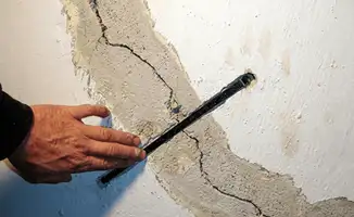 A wall with a large crack is being inspected by a professional in Naperville, IL